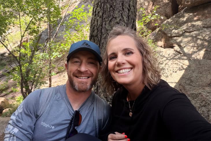 a couple sitting outside in the woods smiling