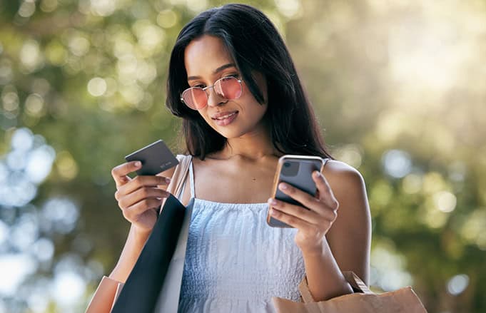 Woman on shopping trip who is using her debit card and consulting her phone.