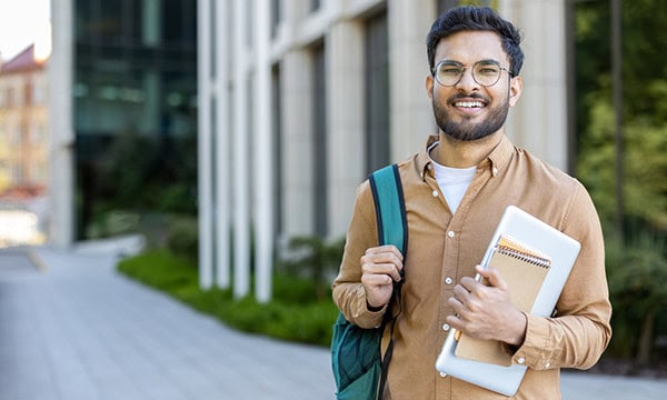 Young man headed to class on modern college campus