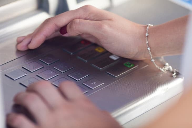 Woman guarding her ATM while withdrawing cash at an ATM