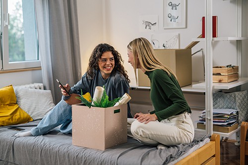 Two female students unpacking in college dorm room