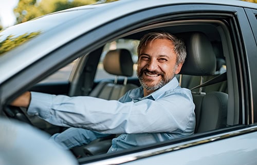 Happy man driving a new car off the dealership lot