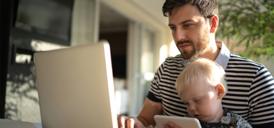 Male with child in his lap using a laptop computer