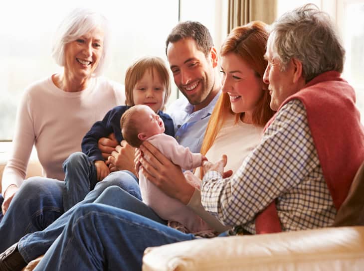 Extended family sitting on a sofa with a newborn