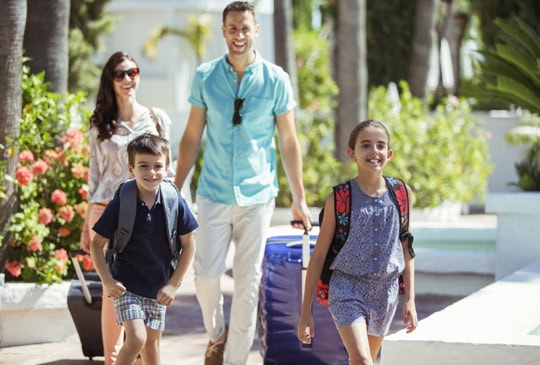 Young family of 4 arriving at a tropical vacation hotel