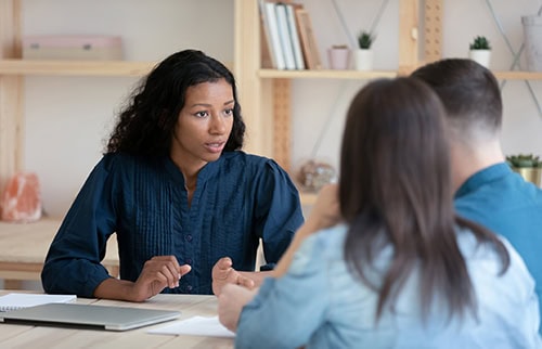 Female loan officer consulting young couple at office meeting
