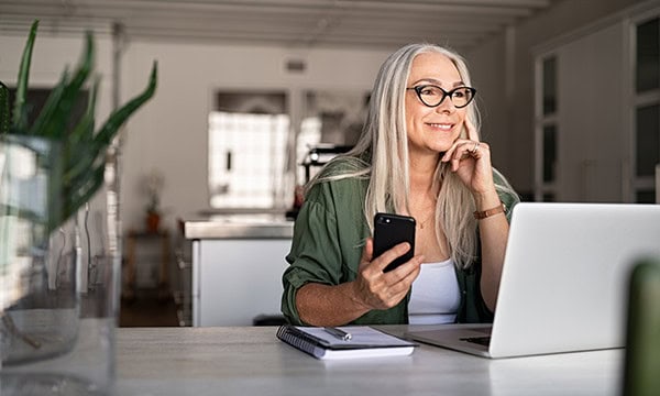 Woman looking thoughtful with a smart phone in her hand