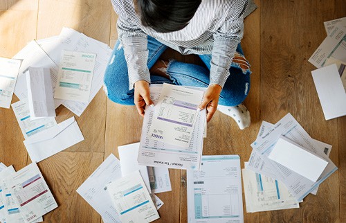 person sitting on floor surrounded by bills