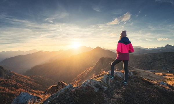 Female mountain climber watching a sunrise in the mountains