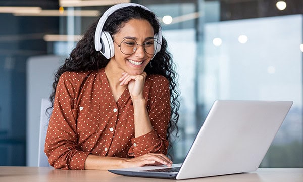 Woman with headphones typing on a laptop computer