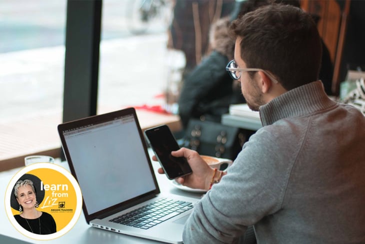 man with phone in hand sitting with laptop