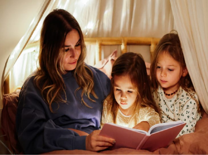 Mother reading to daughters in bed