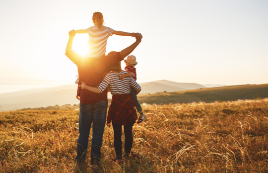 Family in field watching sunrise