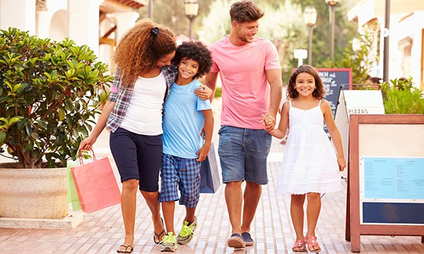 Parents and two children walking along beautiful street with shopping bags.