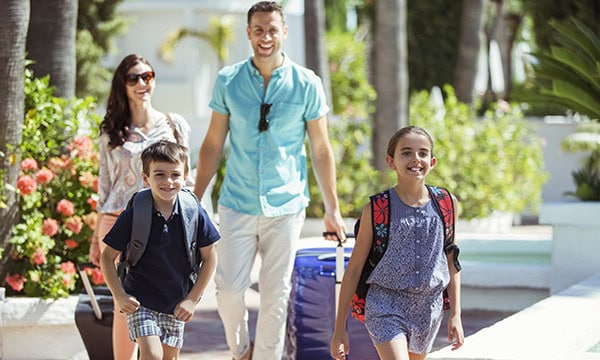 Family with suitcases walking through a beach resort