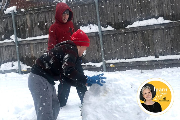 two boys making a big snowball