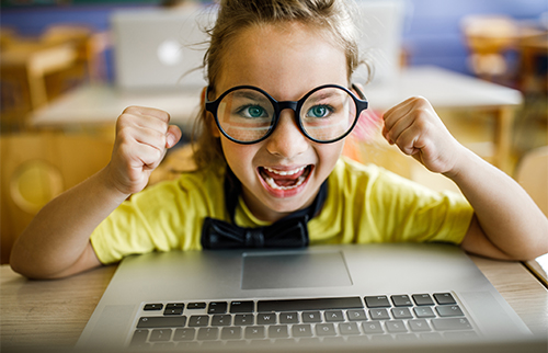 Young girl enthusiastically using laptop computer