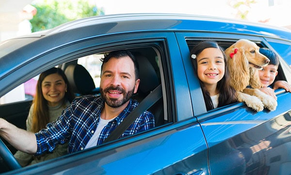 Family group with dog running errands in car