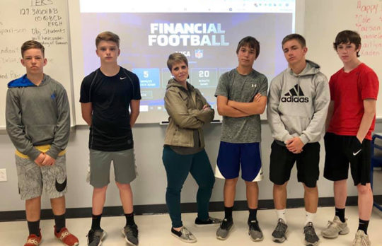 Group of young teens playing Financial Football with teacher
