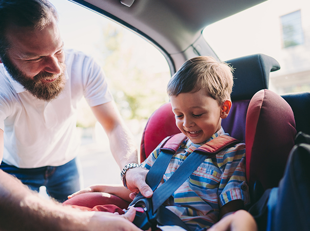 man putting toddler in car seat