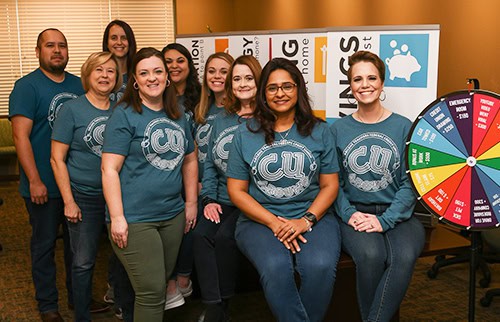 Group of employees standing in front of financial literacy classroom display