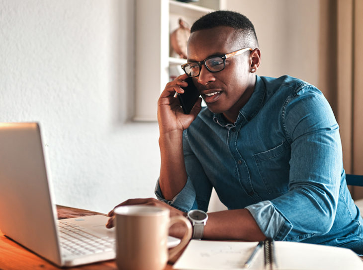 man at computer on phone