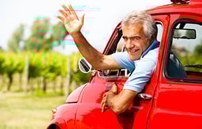 man in red vintage car waving