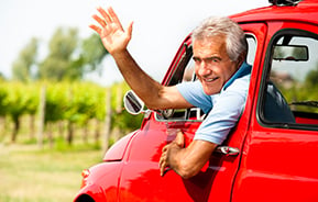 man in red vintage car waving