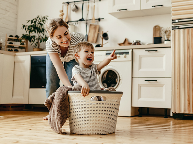 mother pushing son in laundry basket