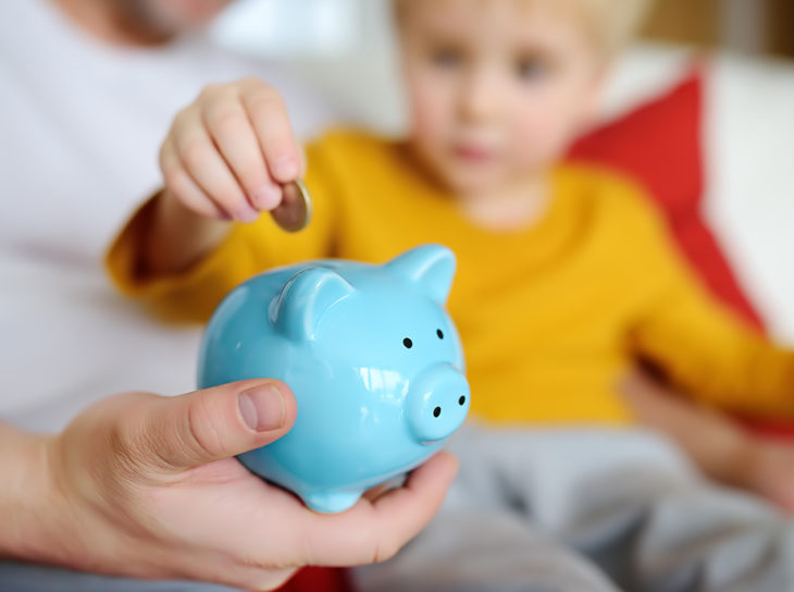 Child depositing coins in piggy bank