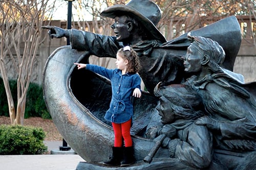 Young girl posed by Santa Calls statue