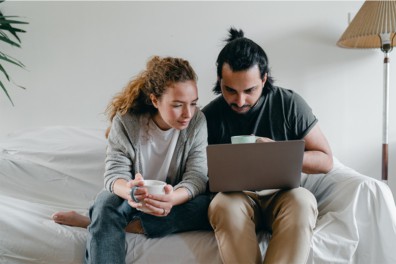 couple sitting on bed with laptop